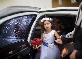 little girl in a white dress coming out of a limousine