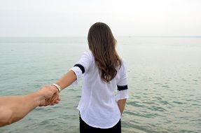 girl by the sea holding her hand