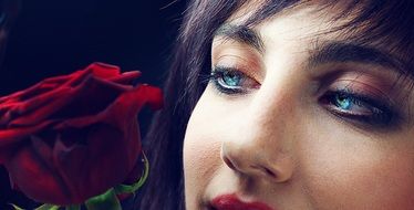 face of a girl near a red rose