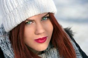 girl with red hair in a white hat in winter