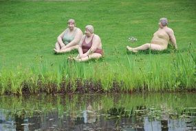 sculptures of full ladies on the shore of the pond