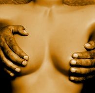 dark skin man’s palms on breasts of caucasian Woman