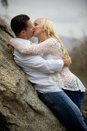 kiss of the young couple near the tree