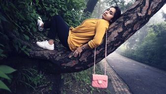 girl posing lying on a tree branch