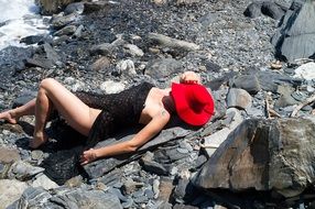 girl lies on stones in a red hat