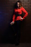 girl in a red blouse by a brick wall