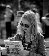 mature Woman reads newspaper at table outdoor, germany, Hamburg