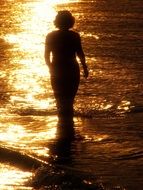 Woman in long dress stands at sunset Golden Sea