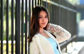 young woman leaning on the fence