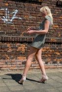 girl in a short dress near a brick wall