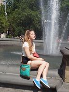 happy girl sitting by the fountain in New York, United States