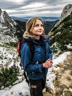 woman in a blue jacket actively travels in the mountains