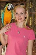 A macaw parrot sits on a girl’s shoulder
