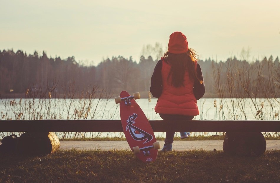 Girl with Longboard rests on bench