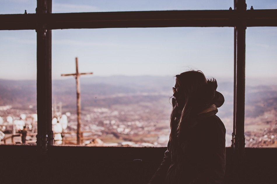silhouette of female person in winter clothes at window