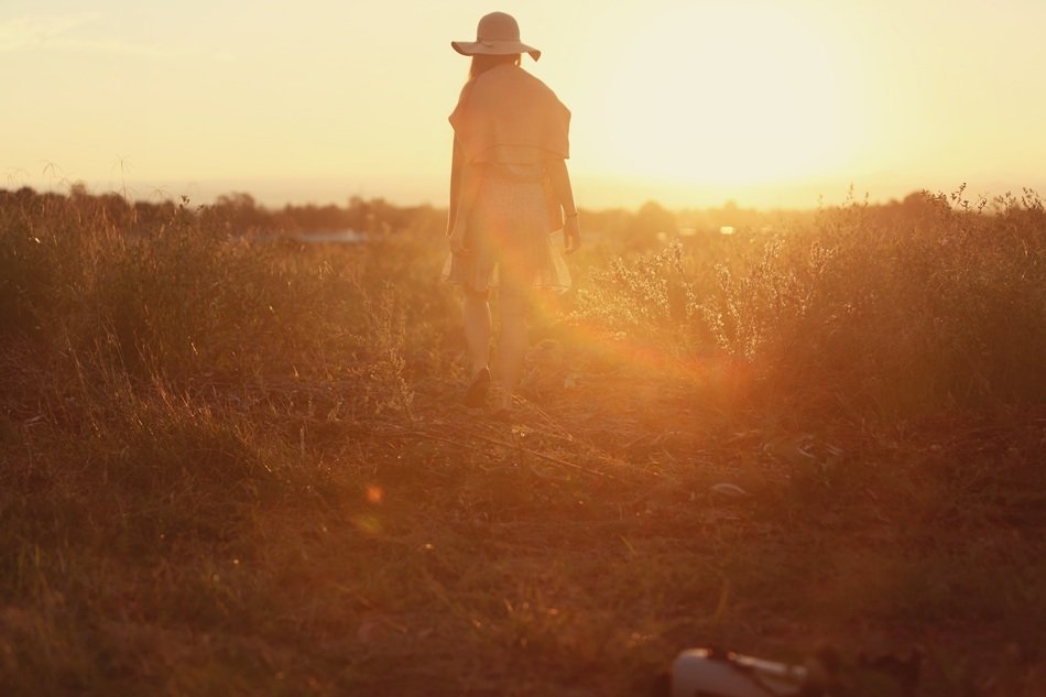 girl in a straw hat in countryside at sunset