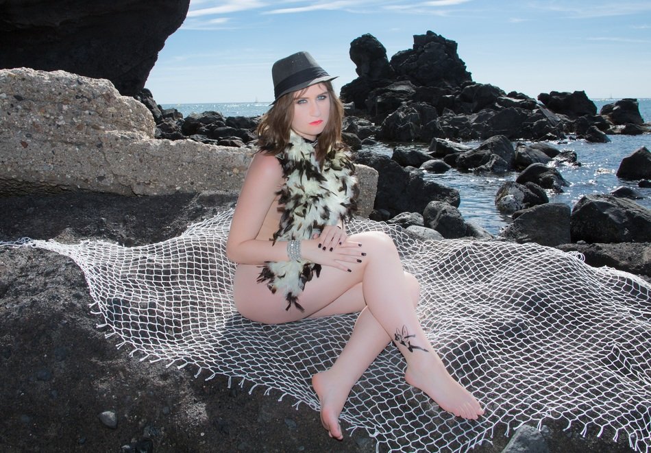 sexy caucasian girl sits on rock at sea