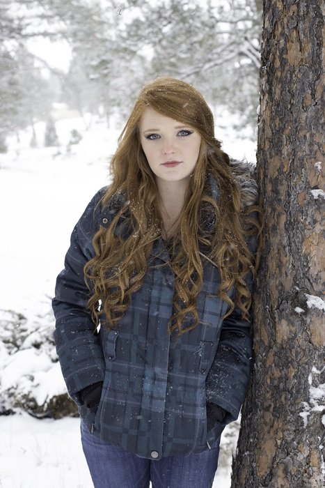 girl in curly hair near a tree on a background of a winter forest