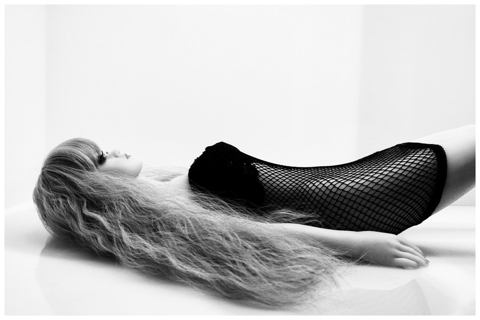 a doll in a black dress lies on the ground
