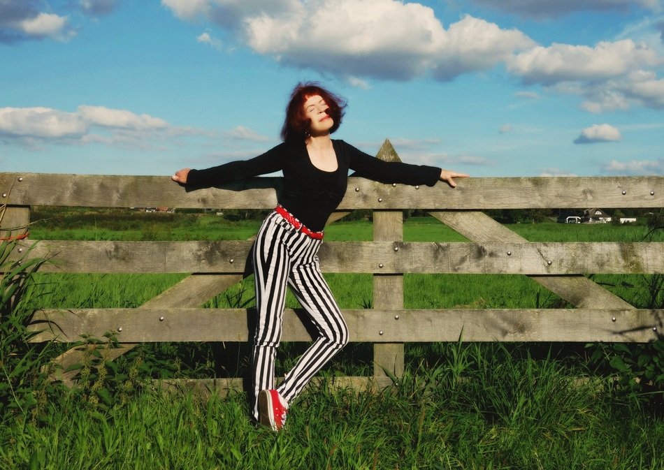 girl in striped pants posing near the fence