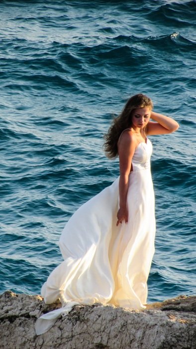 woman in romantic white dress on the rock