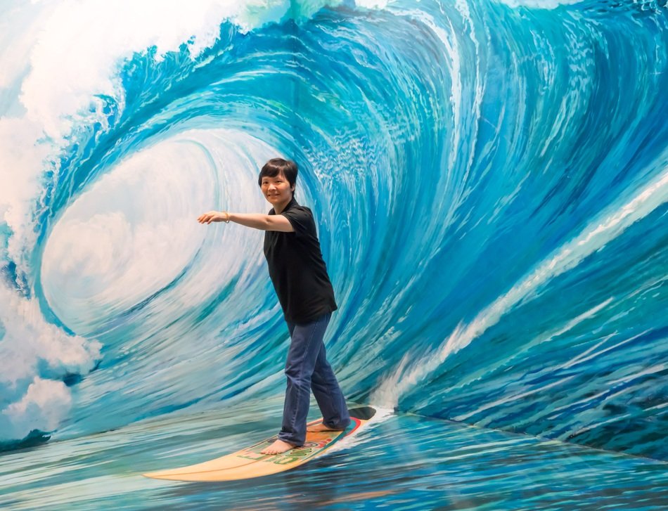 woman stands on a board on a wave