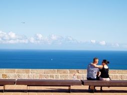 Loving couple is sitting on a bench on the promenade