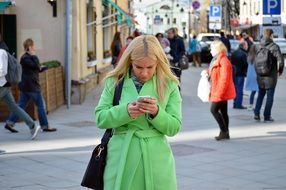 young girl in a green coat walks down the street
