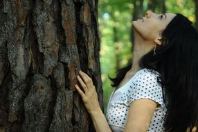 pretty woman touching tree bark
