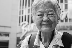 elderly asian with smile in black and white background