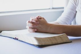 Folded hands on a Christian bible