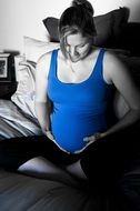 pregnant woman in blue t-shirt on the bed