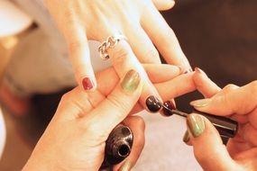 Beauty womanâs Hands painting young girlâs nails, manicure