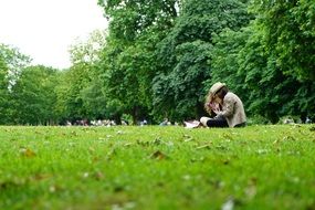 Girl sits on grass In Summer Park