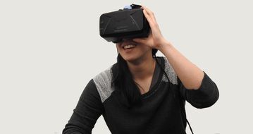 young woman in virtual reality on grey background