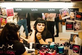 young Woman doing makeup at mirror