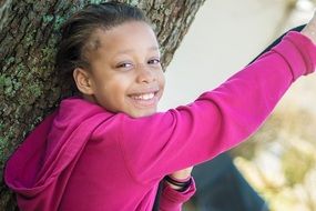 Smiling child Girl at tree trunk