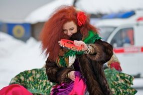 red-haired girl in winter clothes with a tambourine in Russia