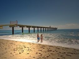 young couple on the background of a long wooden pier on the sea