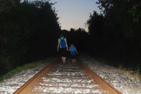 child Boy and Woman Walking together on Railway at dusk