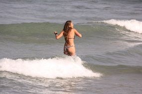 A girl stands on the waves in the ocean in Brazil