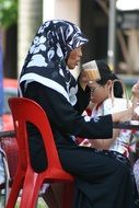 elderly asian woman drinks coffee in a street cafe