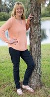 blonde woman leaning on tree trunk