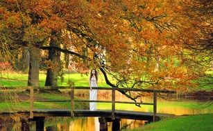 young Woman stands on bridge in beautiful Autumn park