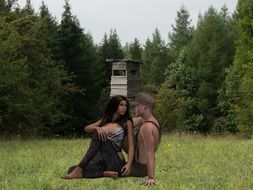 man and woman are sitting on the green grass