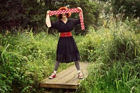 girl stands on a wooden board among the grass