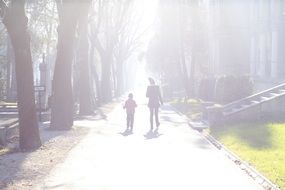 Kid and Mom walking on alley in park