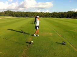 beautiful girl plays golf on a green field