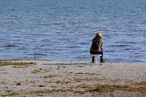 Person is sitting on the chair near the lake