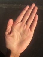 man's left hand on a dark background
